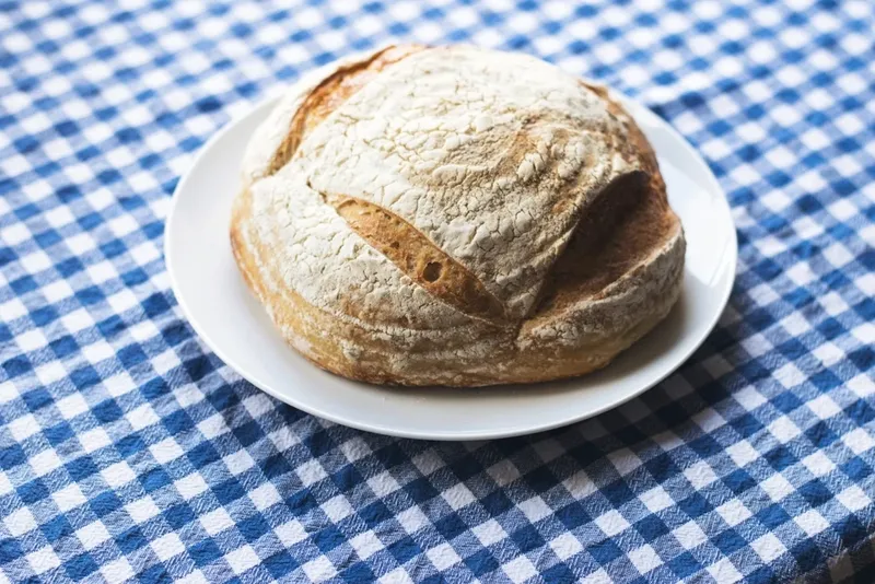 A round sourdough loaf on a checked tablecloth